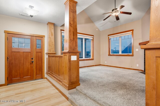 foyer entrance with light wood-type flooring, decorative columns, a textured ceiling, ceiling fan, and lofted ceiling