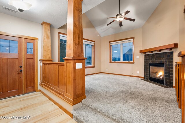 living room with light carpet, a textured ceiling, ceiling fan, lofted ceiling, and a tiled fireplace