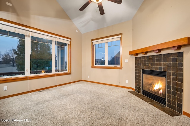 unfurnished living room featuring dark colored carpet, a tile fireplace, lofted ceiling, and ceiling fan