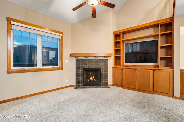 unfurnished living room with vaulted ceiling, ceiling fan, a tile fireplace, and carpet floors