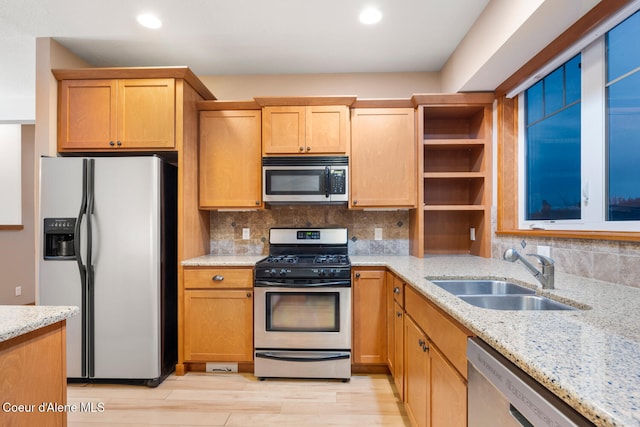 kitchen with sink, light wood-type flooring, backsplash, light stone countertops, and stainless steel appliances