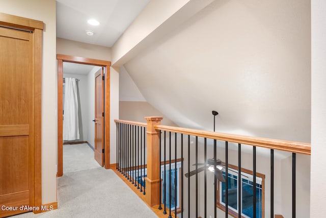 hallway featuring light colored carpet and lofted ceiling