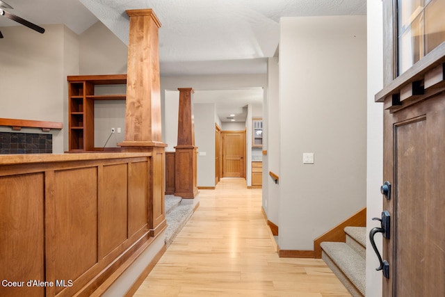 entryway featuring a textured ceiling, light hardwood / wood-style flooring, and ornate columns