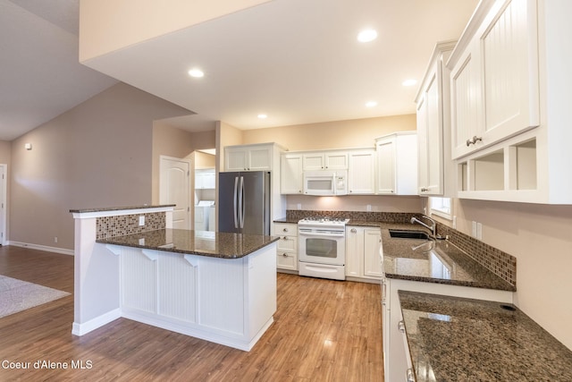 kitchen with white appliances, sink, dark stone countertops, light hardwood / wood-style floors, and white cabinetry