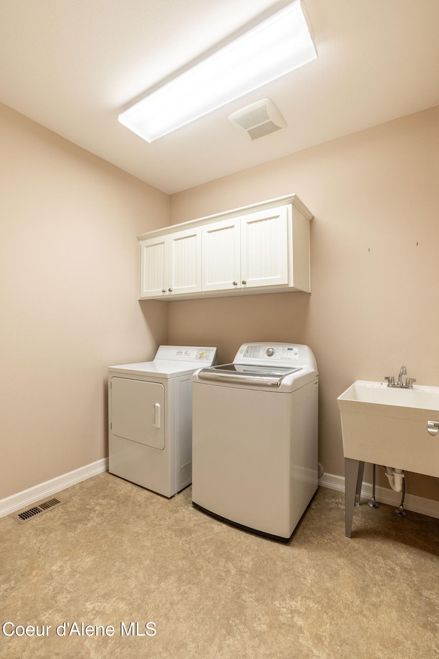 clothes washing area with cabinets, sink, light colored carpet, and washing machine and clothes dryer