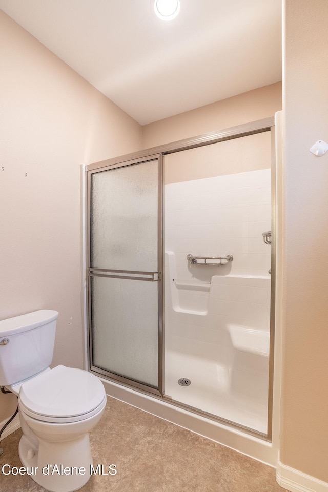 bathroom featuring toilet and a shower with door