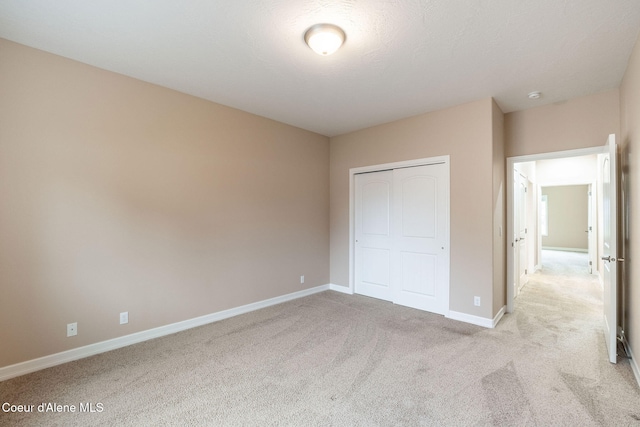 unfurnished bedroom with light colored carpet and a closet