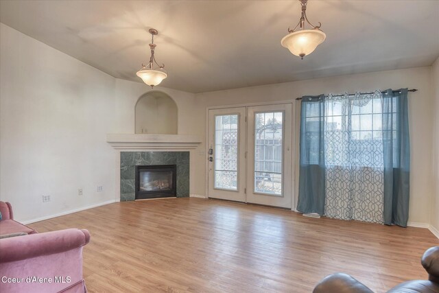 living room featuring a high end fireplace, baseboards, and wood finished floors