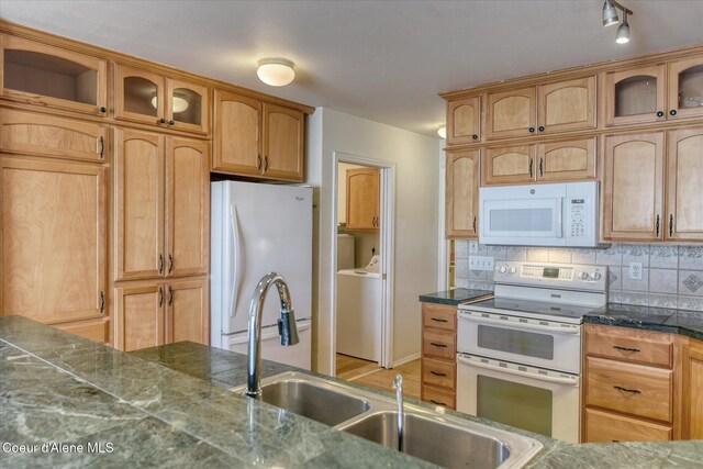 kitchen featuring white appliances, washer / dryer, glass insert cabinets, and tasteful backsplash