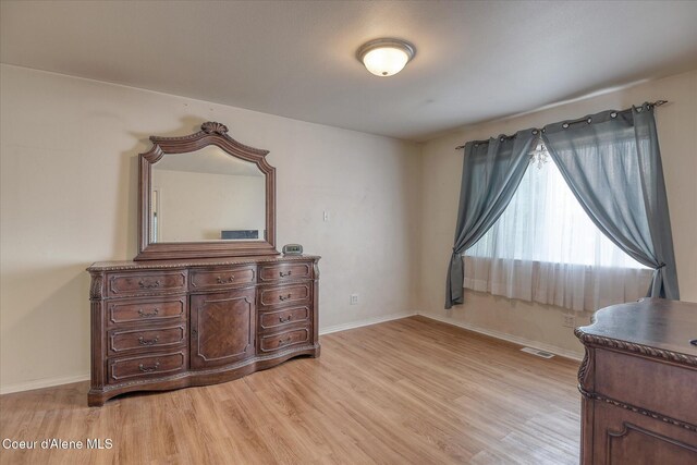 bedroom with baseboards, visible vents, and light wood finished floors