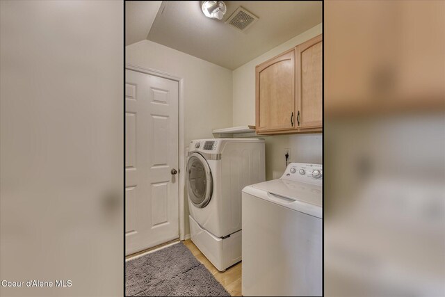 clothes washing area featuring visible vents, light wood-style flooring, cabinet space, and washing machine and clothes dryer