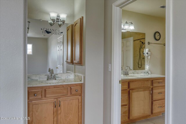 bathroom featuring a sink, two vanities, and a chandelier