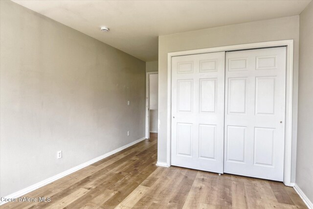 unfurnished bedroom with baseboards, wood finished floors, and a closet
