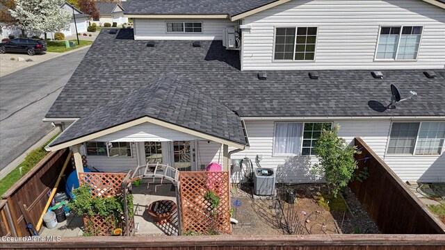 back of property featuring roof with shingles, central air condition unit, and fence