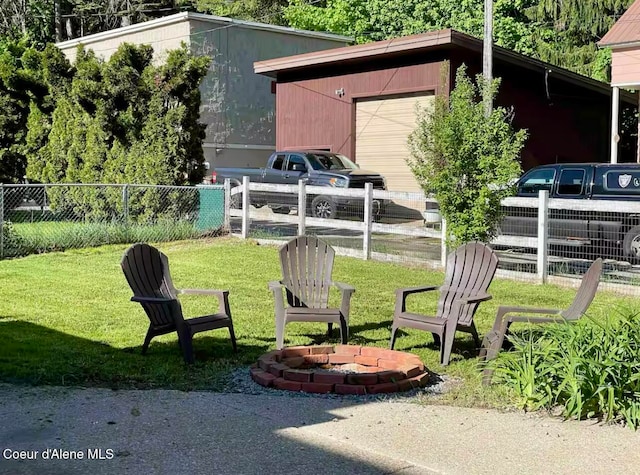 view of yard with an outbuilding, a fire pit, and a garage