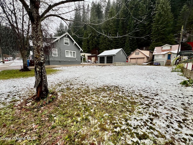 yard layered in snow with an outbuilding and a garage