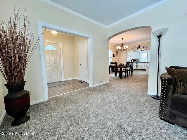 carpeted foyer entrance with a chandelier and crown molding