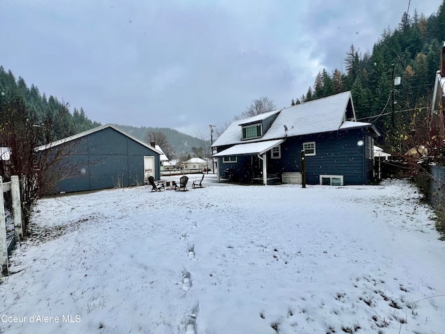 snow covered house featuring an outbuilding