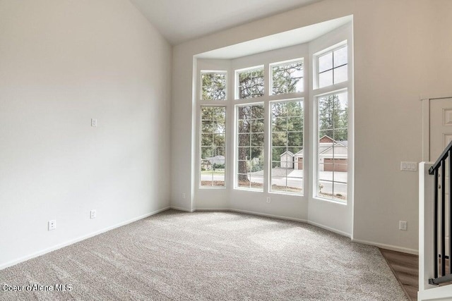 carpeted empty room with plenty of natural light and lofted ceiling