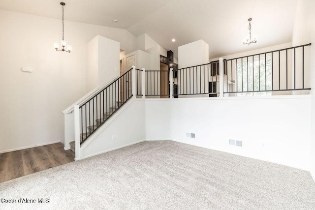 unfurnished living room with a chandelier, vaulted ceiling, and wood-type flooring