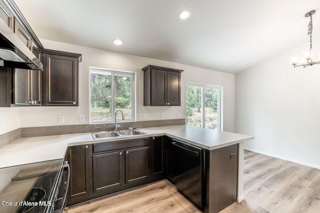 kitchen with kitchen peninsula, sink, decorative light fixtures, range, and black dishwasher