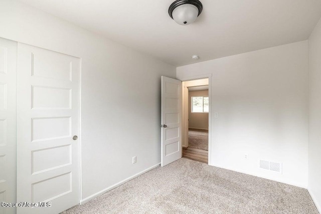 unfurnished bedroom featuring light colored carpet and a closet