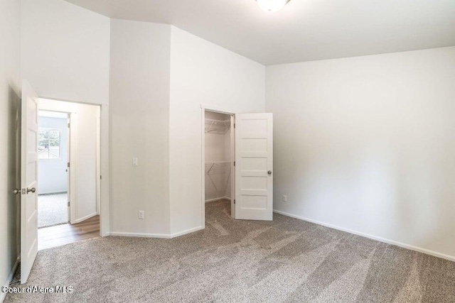 unfurnished bedroom featuring carpet, a walk in closet, and a closet