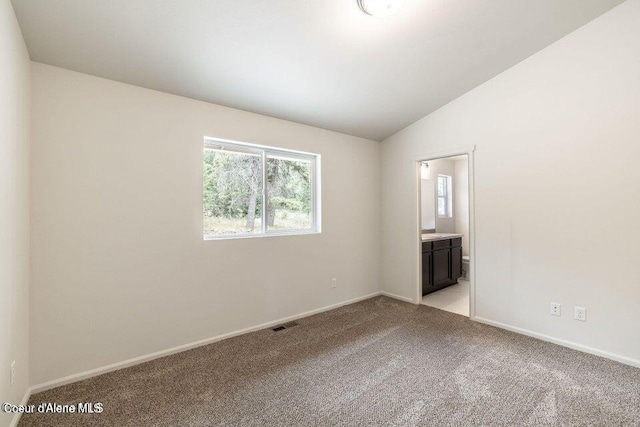 carpeted empty room with vaulted ceiling