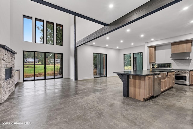 kitchen with appliances with stainless steel finishes, a kitchen island, a kitchen bar, a fireplace, and beam ceiling