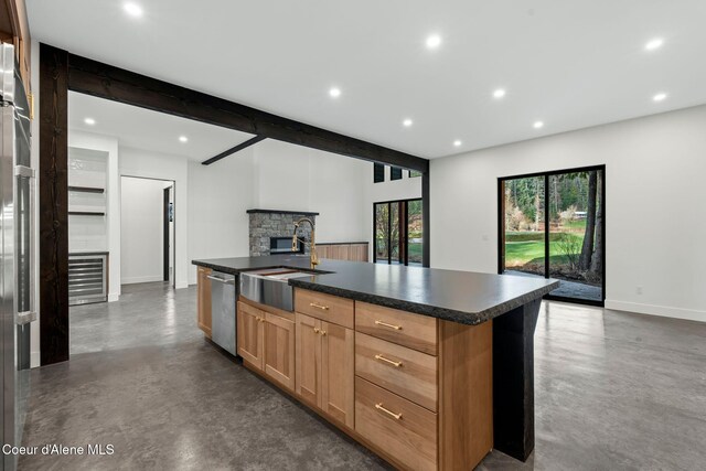 kitchen with concrete floors, a stone fireplace, open floor plan, and dark countertops