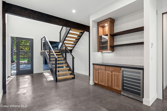 bar with a dry bar, wine cooler, concrete flooring, stairway, and backsplash