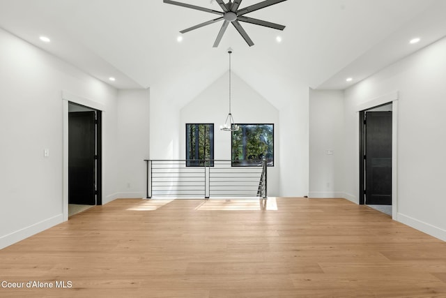 interior space with light wood-style flooring, ceiling fan with notable chandelier, lofted ceiling, and recessed lighting