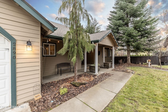 view of exterior entry with a patio area and a lawn