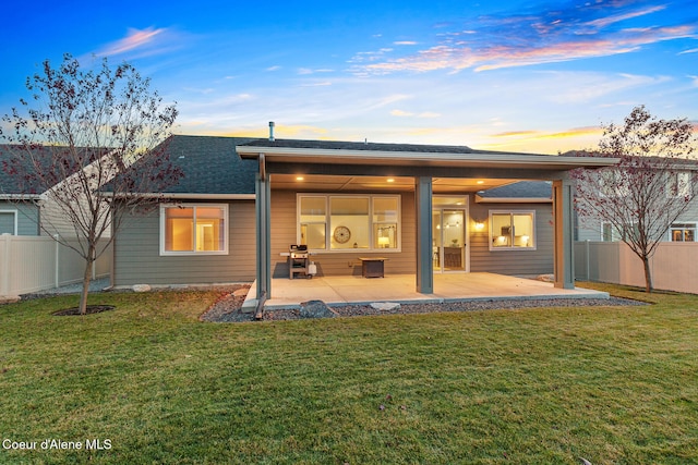 back house at dusk with a patio area and a yard