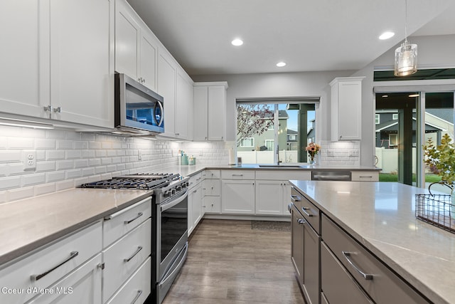 kitchen featuring sink, stainless steel appliances, light stone counters, light hardwood / wood-style floors, and white cabinets