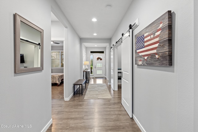 corridor featuring a barn door and hardwood / wood-style flooring