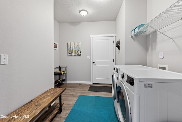 clothes washing area with hardwood / wood-style floors, washing machine and dryer, and a textured ceiling