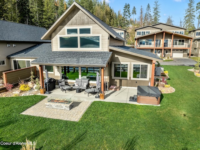 back of house featuring a patio area, a yard, an outdoor living space with a fire pit, and a hot tub