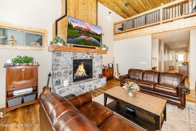 living room with a stone fireplace, hardwood / wood-style floors, high vaulted ceiling, and wood ceiling