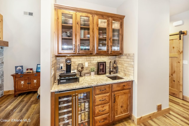 bar with decorative backsplash, sink, beverage cooler, and light hardwood / wood-style floors