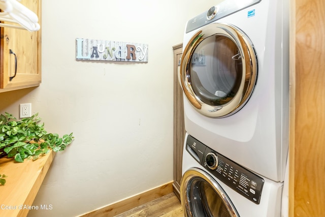 washroom featuring cabinets, hardwood / wood-style floors, and stacked washer and dryer