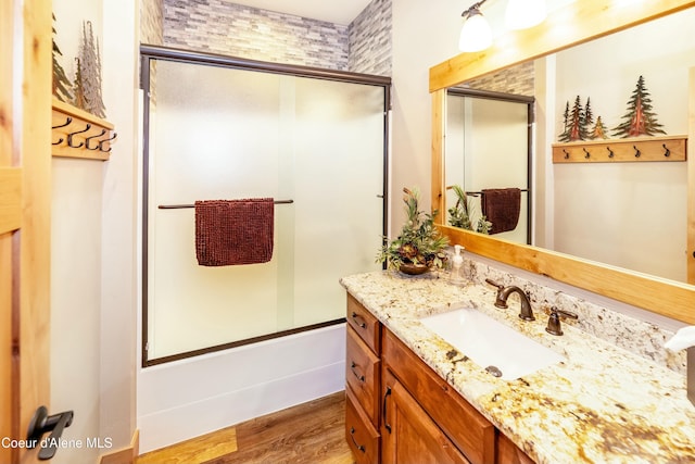 bathroom featuring enclosed tub / shower combo, wood-type flooring, and vanity