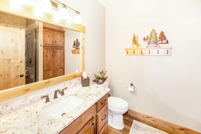 bathroom featuring hardwood / wood-style floors, vanity, toilet, and tiled shower