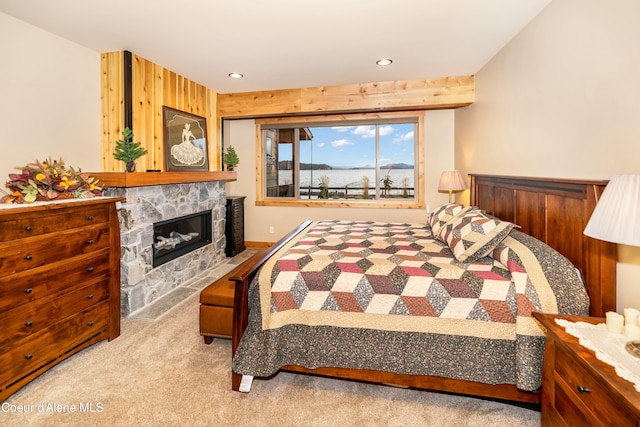 bedroom with light colored carpet, a stone fireplace, and wooden walls