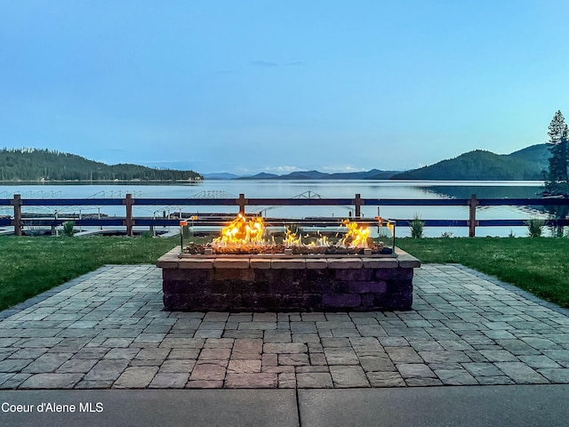 view of patio with an outdoor fire pit and a water and mountain view