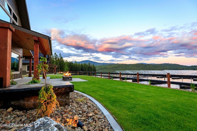 yard at dusk with a fire pit, a boat dock, and a mountain view