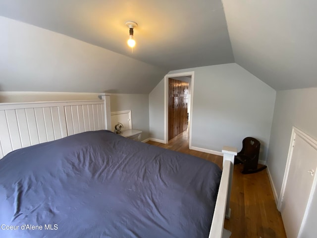 unfurnished bedroom with wood-type flooring and vaulted ceiling