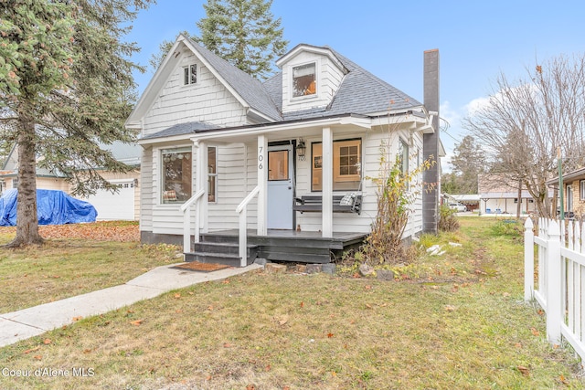 bungalow-style house with an outdoor structure, covered porch, and a front yard