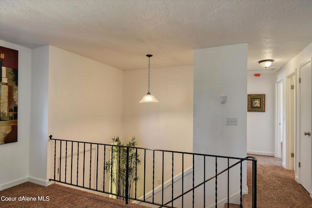 hallway with a textured ceiling and carpet floors