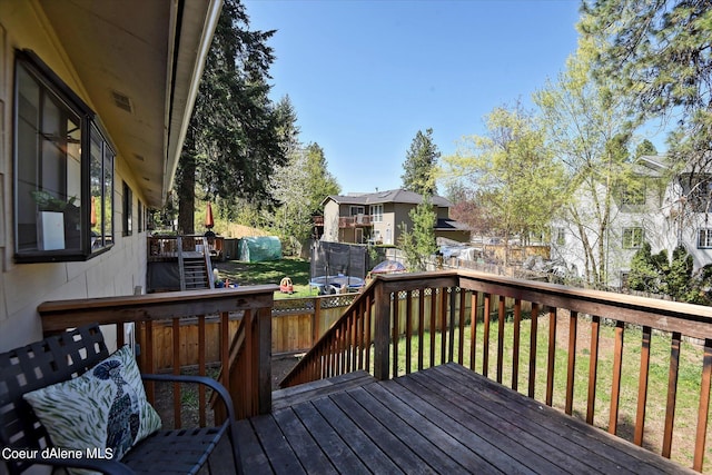 wooden terrace with a lawn and a trampoline